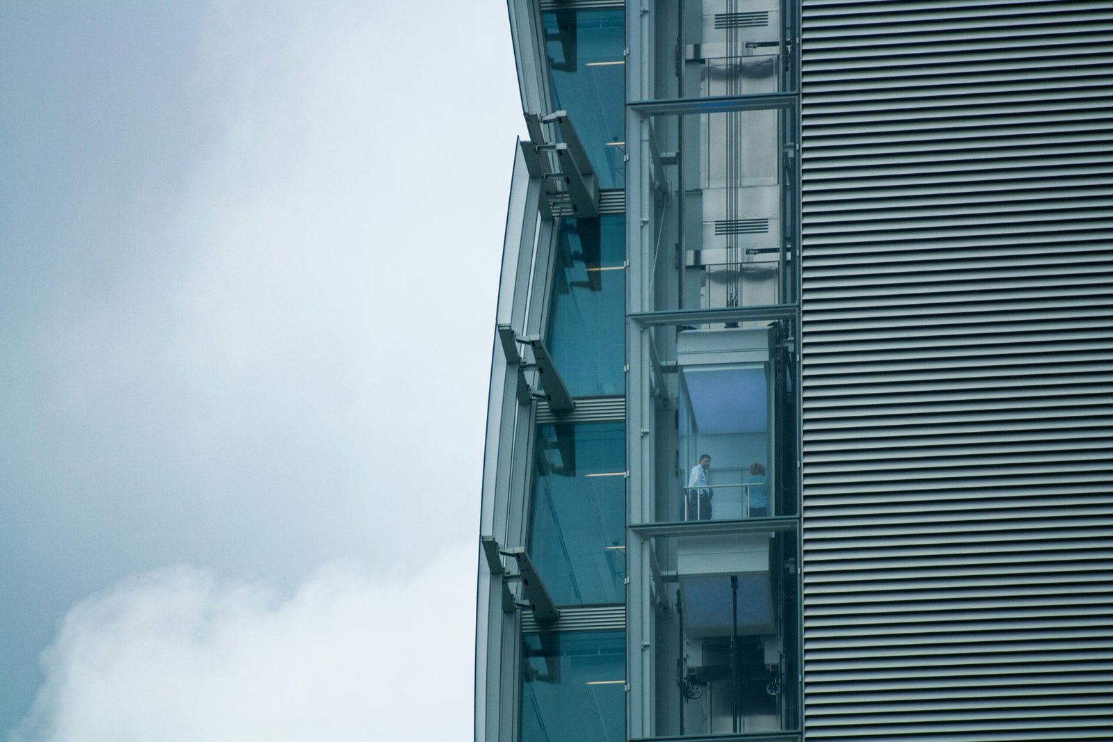 Close-up of a modern building with glass elevators and steel facade in Milano, Italy.
